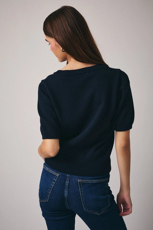 Woman wearing a dark blue sweater and jeans on a plain background