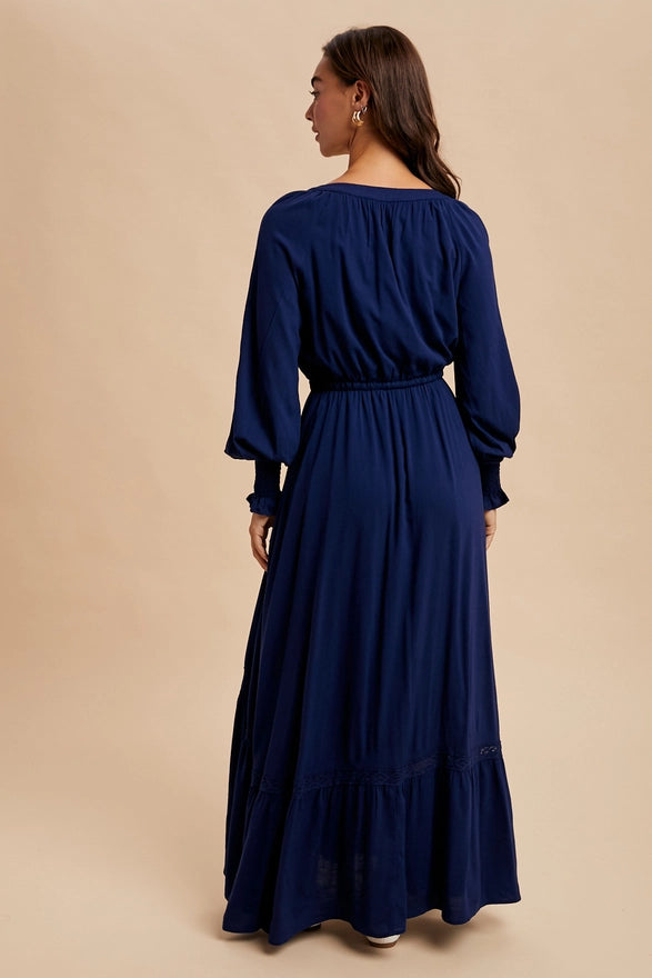 Woman wearing a navy color maxi dress with long sleeves on plain background