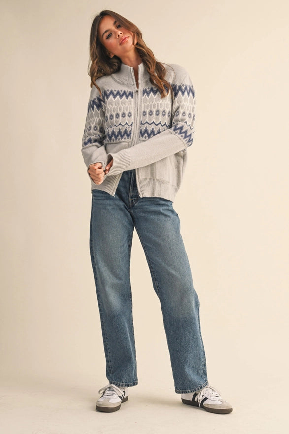 Woman wearing a patterned sweater and jeans on a beige background