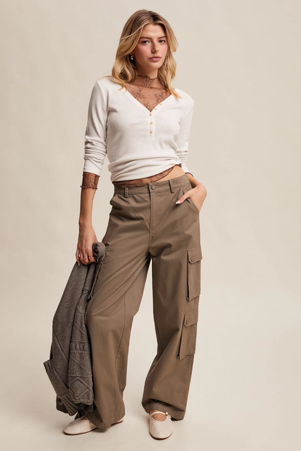Girl wearing mocha colored cargo pants on plain background.
