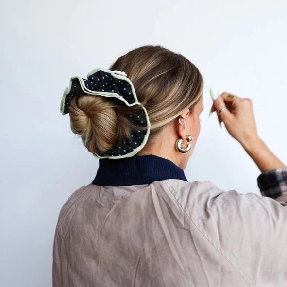 Person styling their hair with a decorative hair clip against a white background