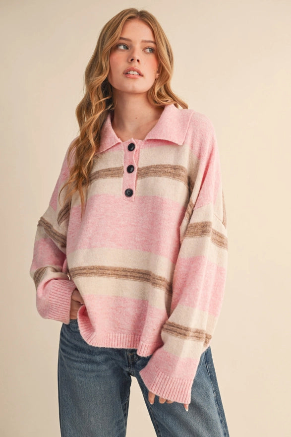 Woman wearing a pink striped sweater with black buttons on a beige background