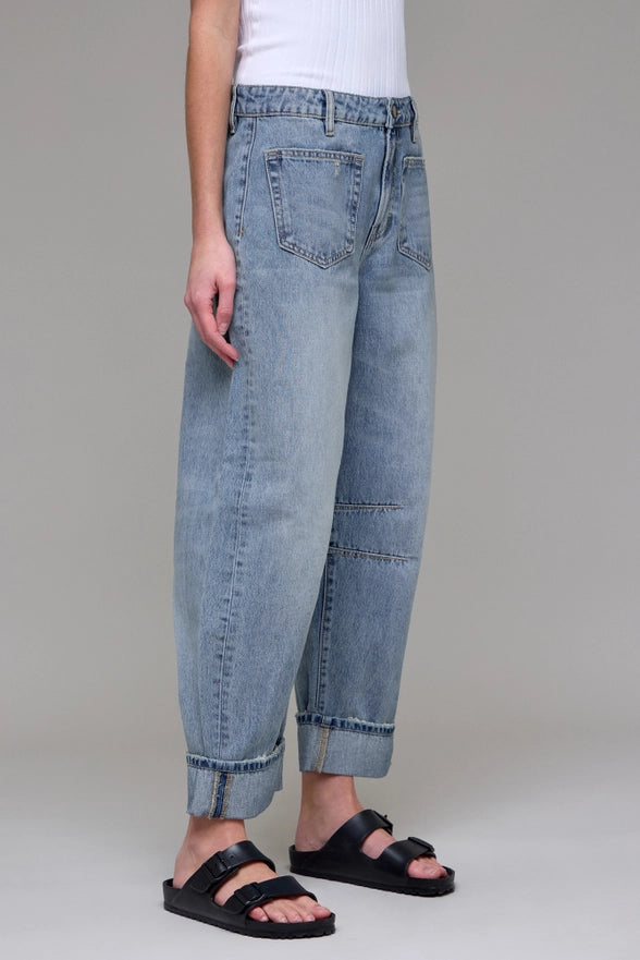 Person wearing light blue jeans and black sandals on a plain background