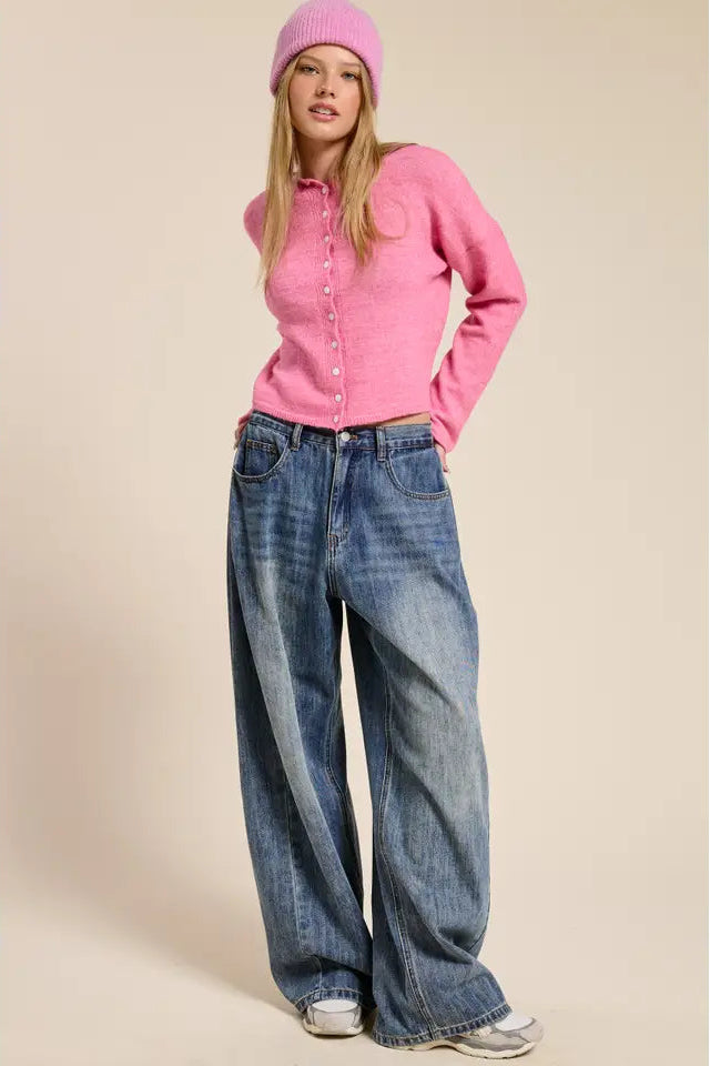 Woman wearing a pink sweater and blue jeans against a beige background
