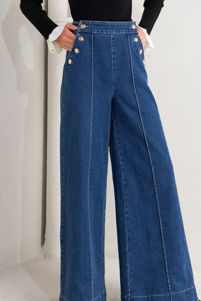 Blue wide-leg jeans with gold buttons on a white background