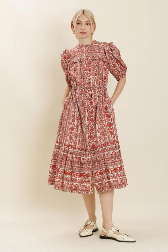 Woman wearing a red floral dress against a plain background