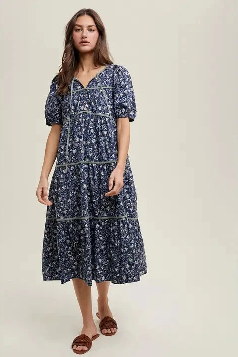 Woman wearing a navy floral dress on a plain background