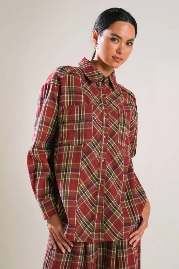 Woman wearing a red plaid shirt and skirt against a plain background