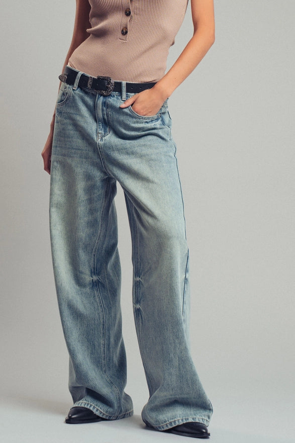 Person wearing light blue jeans and a beige top on a plain background