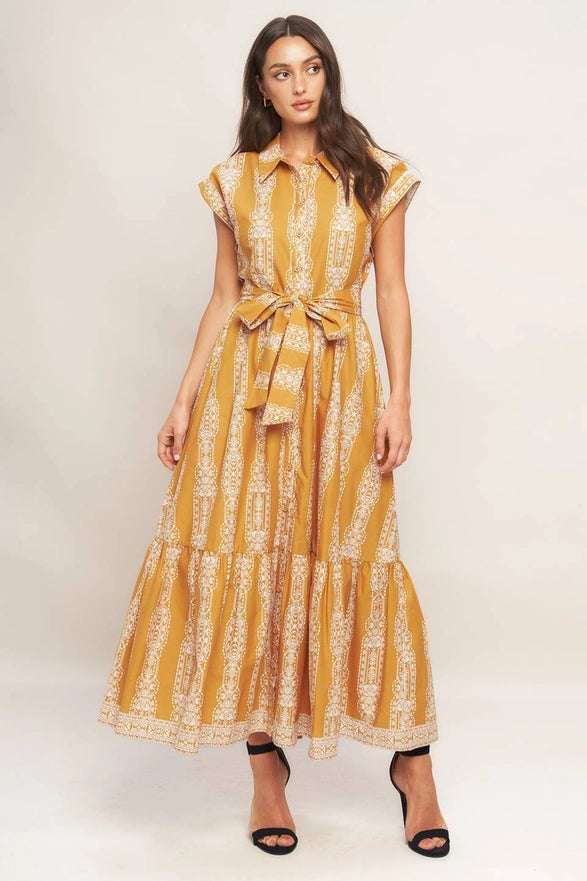 Woman wearing a yellow and white patterned dress on a plain background