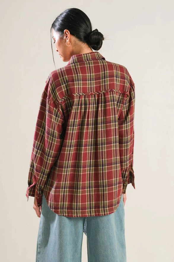Person wearing a red plaid shirt with a neutral background