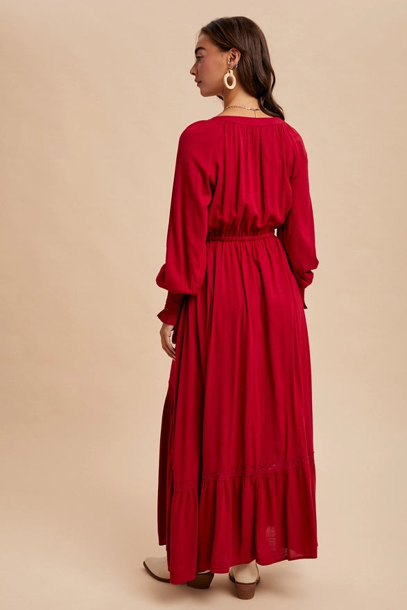 Woman wearing a cherry color maxi dress with long sleeves on plain background