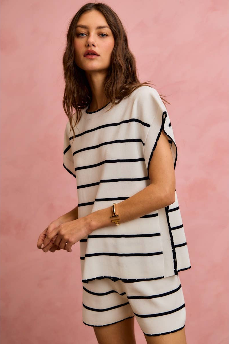 Woman wearing a black and white striped outfit against a pink background
