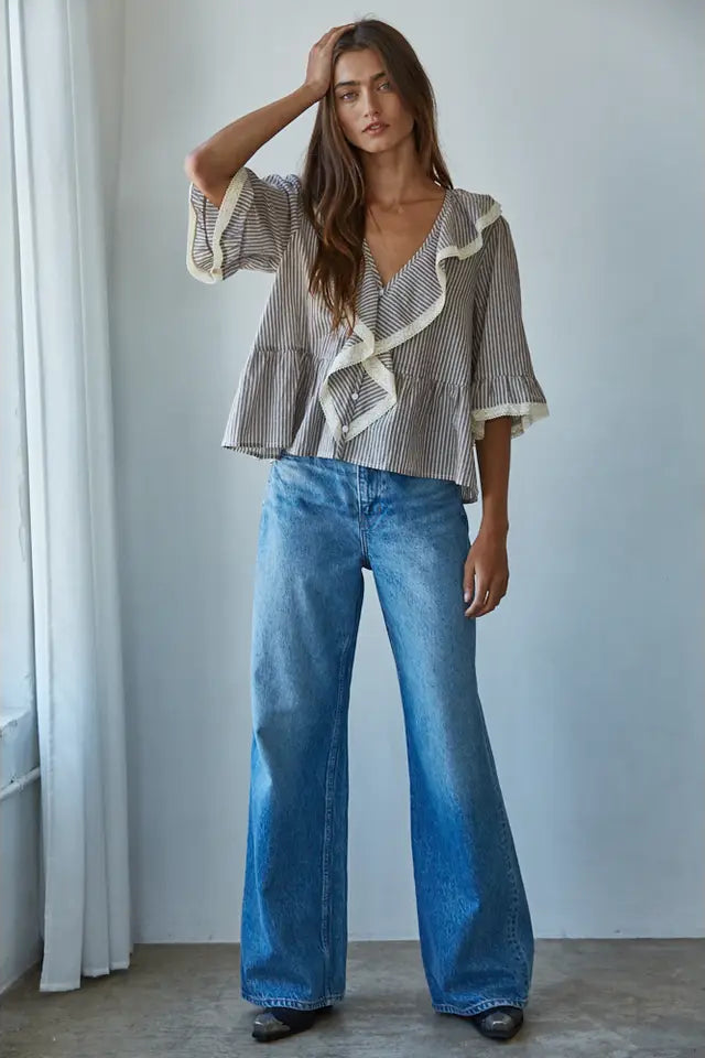 Woman wearing a striped blouse and blue jeans against a neutral background