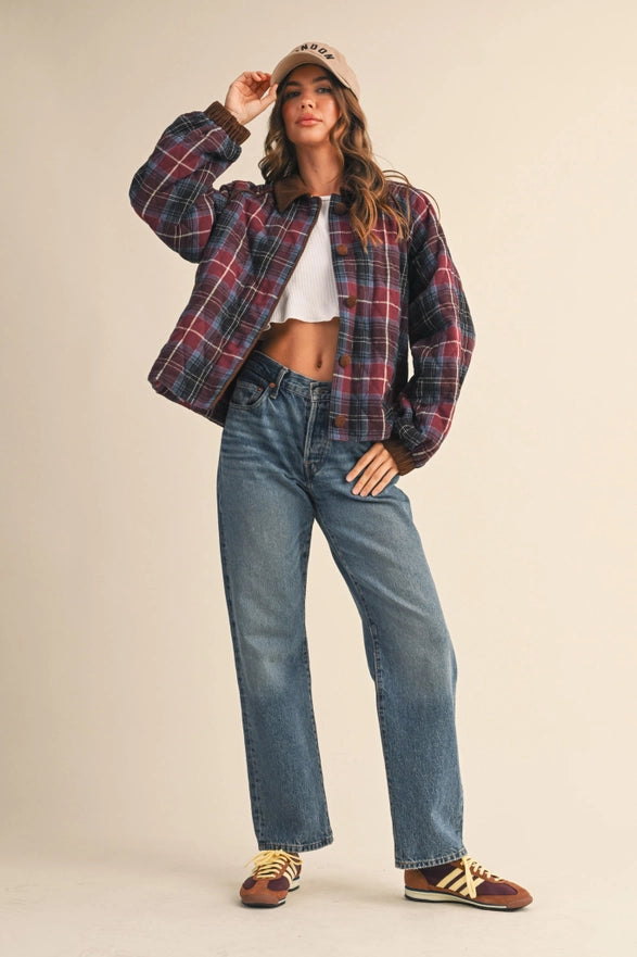 Woman wearing a plaid shirt, jeans, and a cap on a beige background