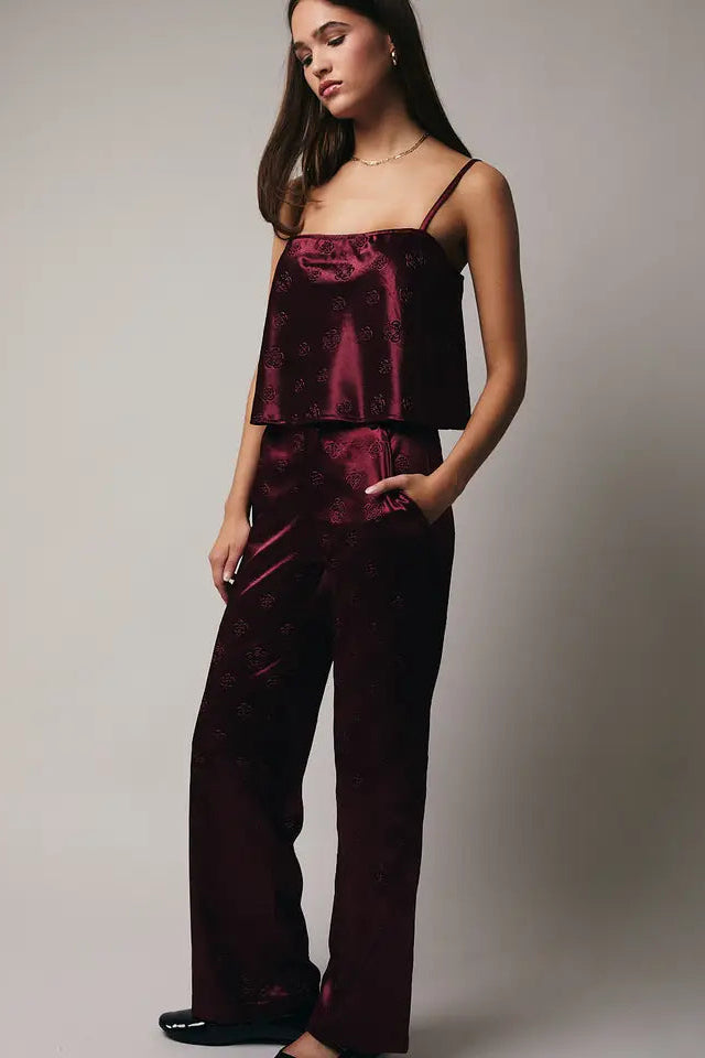 Woman wearing a burgundy satin pajama set against a plain background