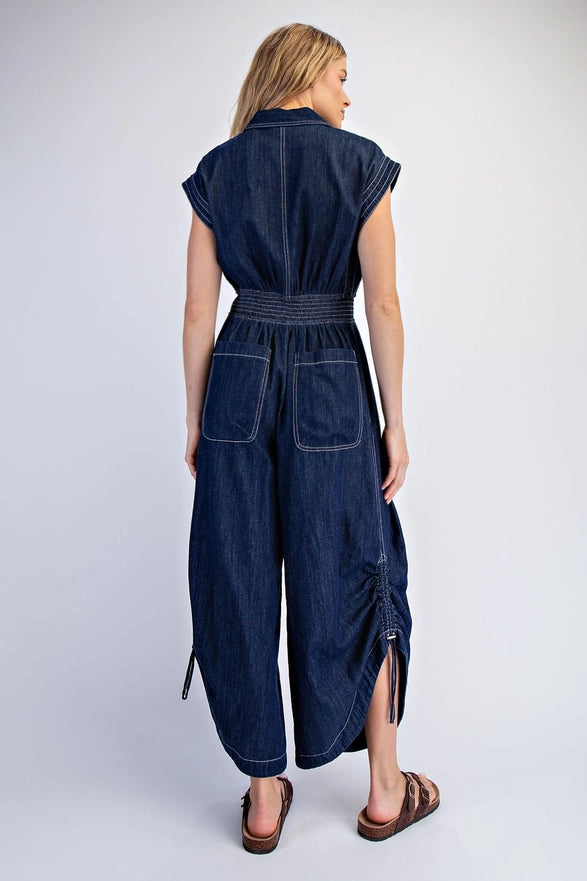 Woman wearing a dark denim jumpsuit on a white background