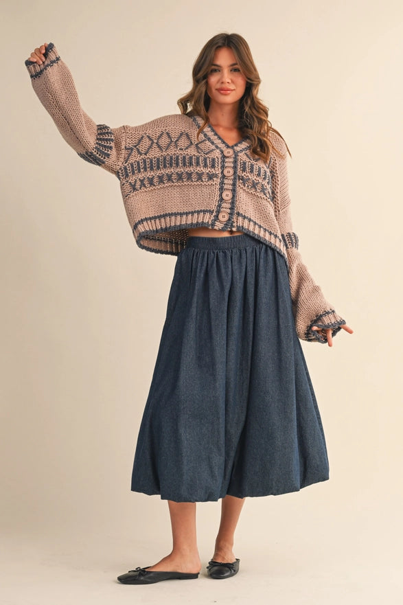 Woman wearing a patterned sweater and blue skirt on a beige background