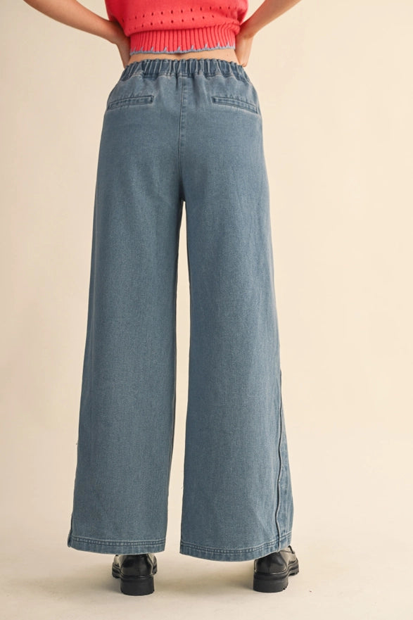 Person wearing blue wide-leg jeans and a red top on a beige background