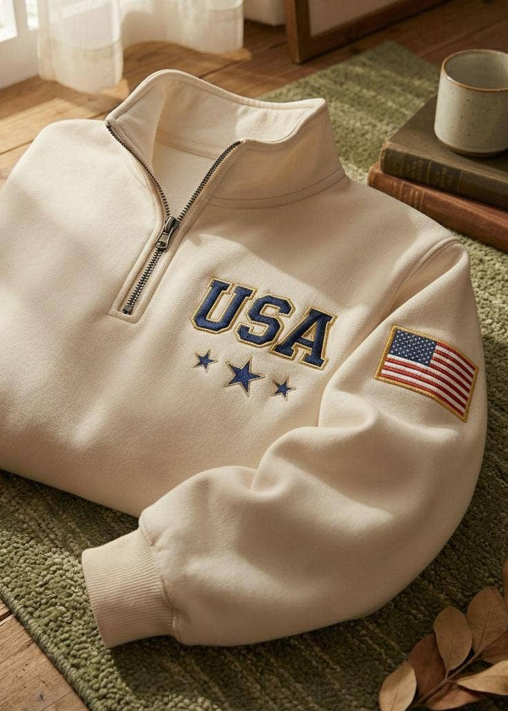 Beige sweatshirt with 'USA' and American flag patch on a green rug.