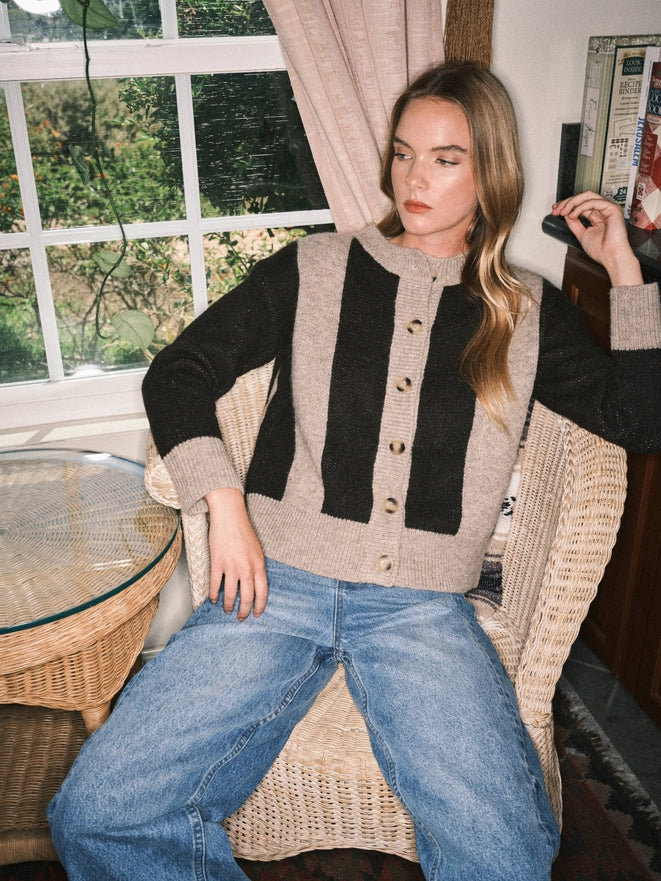 Woman sitting in a chair wearing a striped sweater and jeans in a home setting.