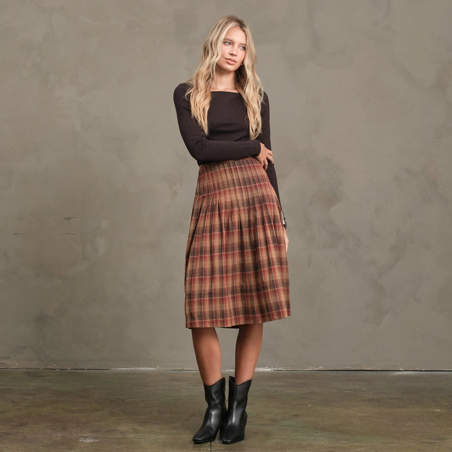 Woman wearing a plaid skirt and black top against a gray background