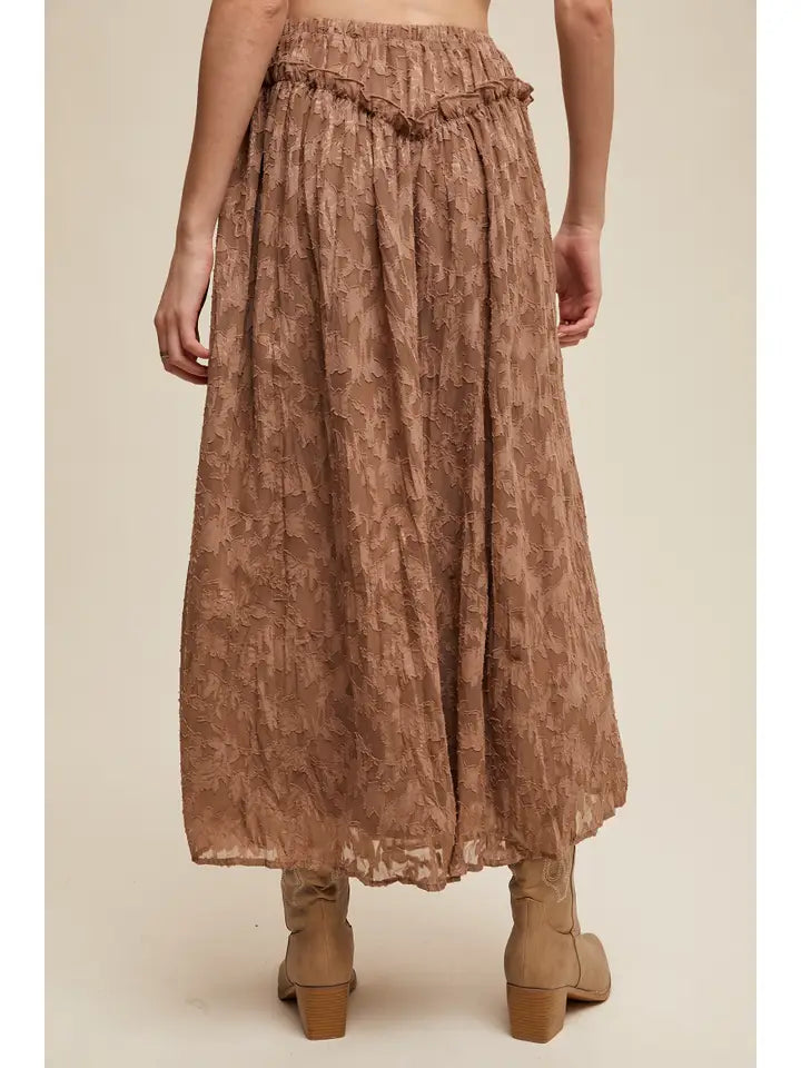 Brown patterned skirt worn by a person on a beige background