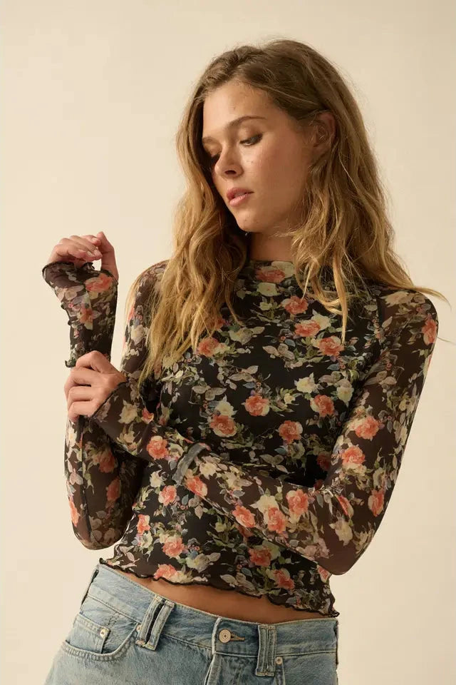 Woman wearing a floral long-sleeve top and jeans against a beige background