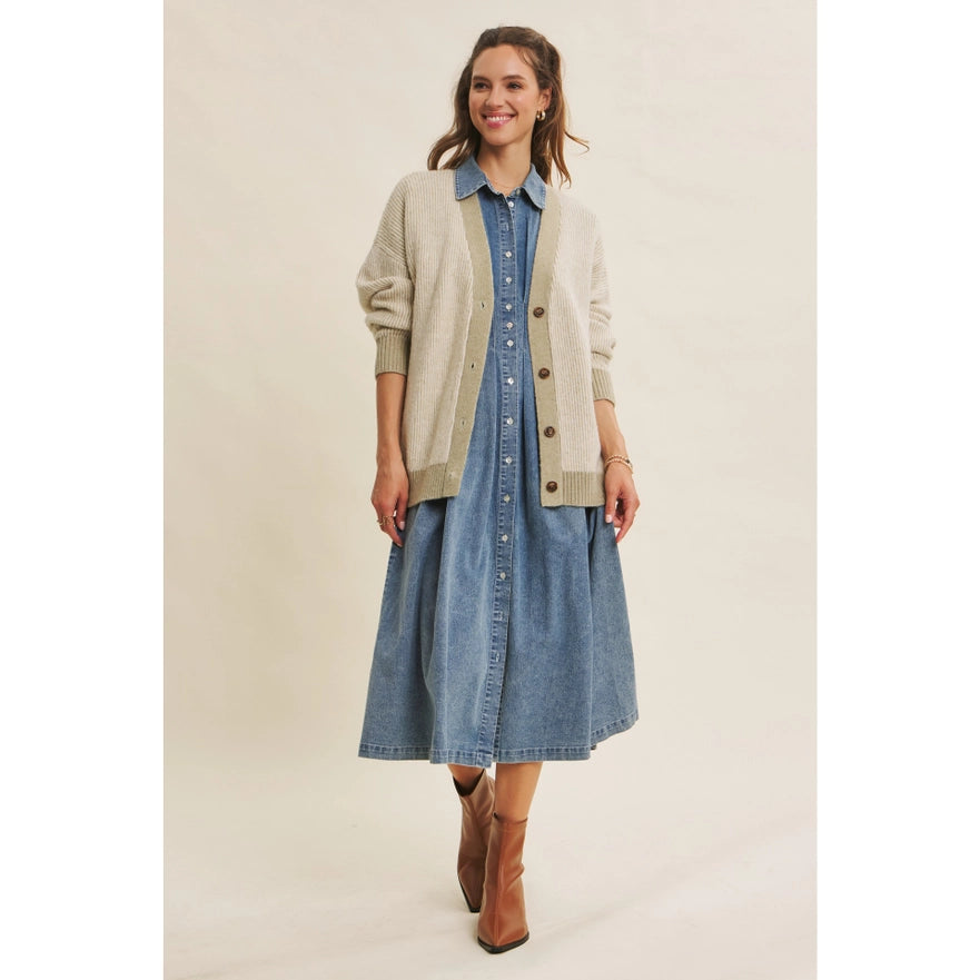 Woman wearing a denim dress with a beige cardigan on a plain background