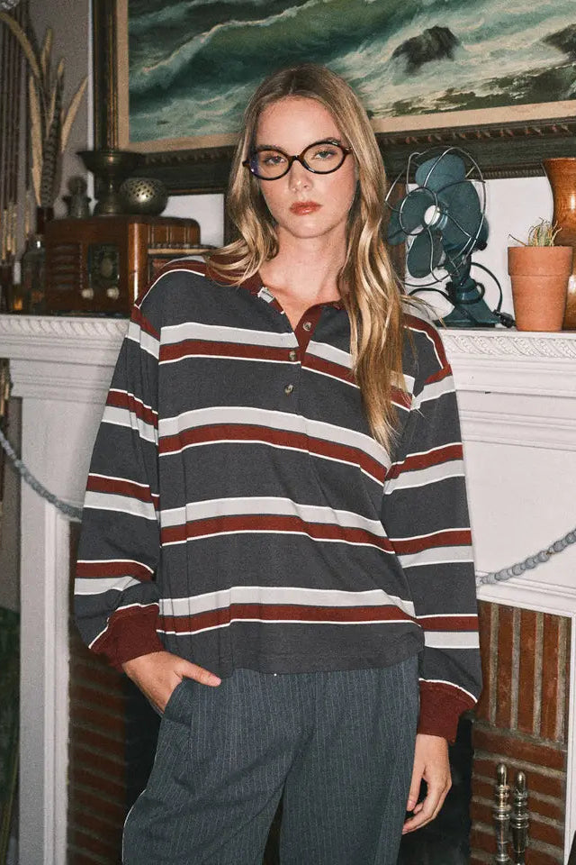 Woman wearing a striped sweater in a room with a fireplace and artwork.