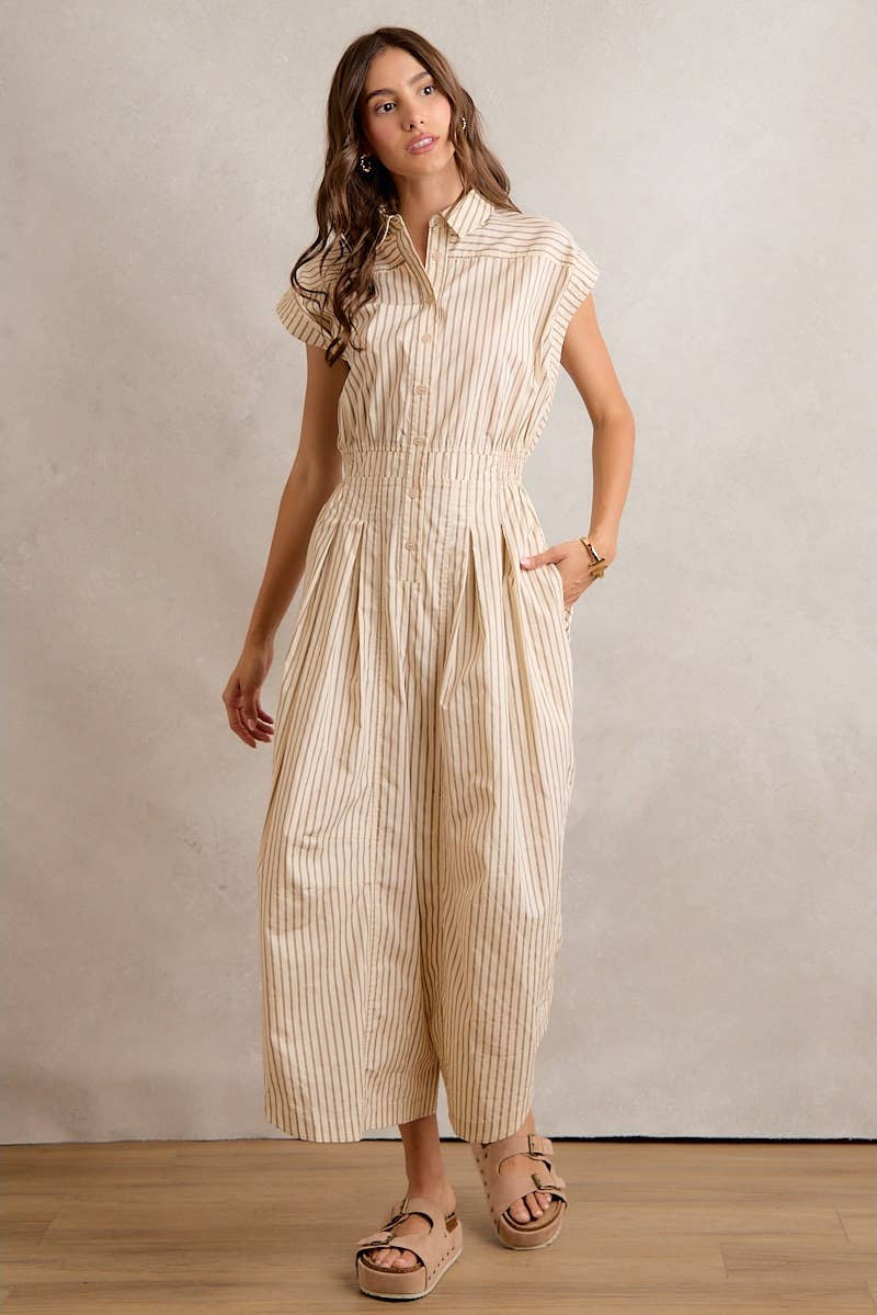 Woman wearing a beige striped jumpsuit against a plain background