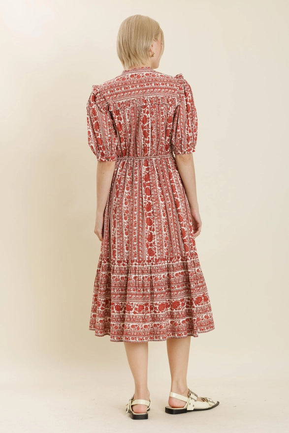 Woman wearing a red patterned dress on a beige background