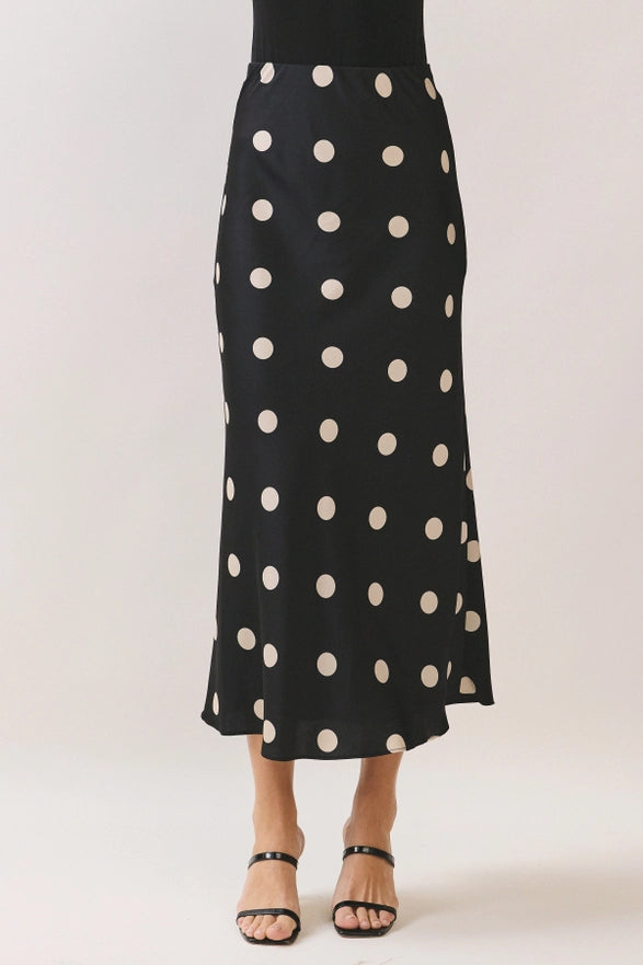 Black skirt with white polka dots worn by a person on a plain background