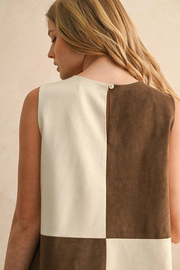 Woman wearing a sleeveless dress with a two-tone design on a beige background
