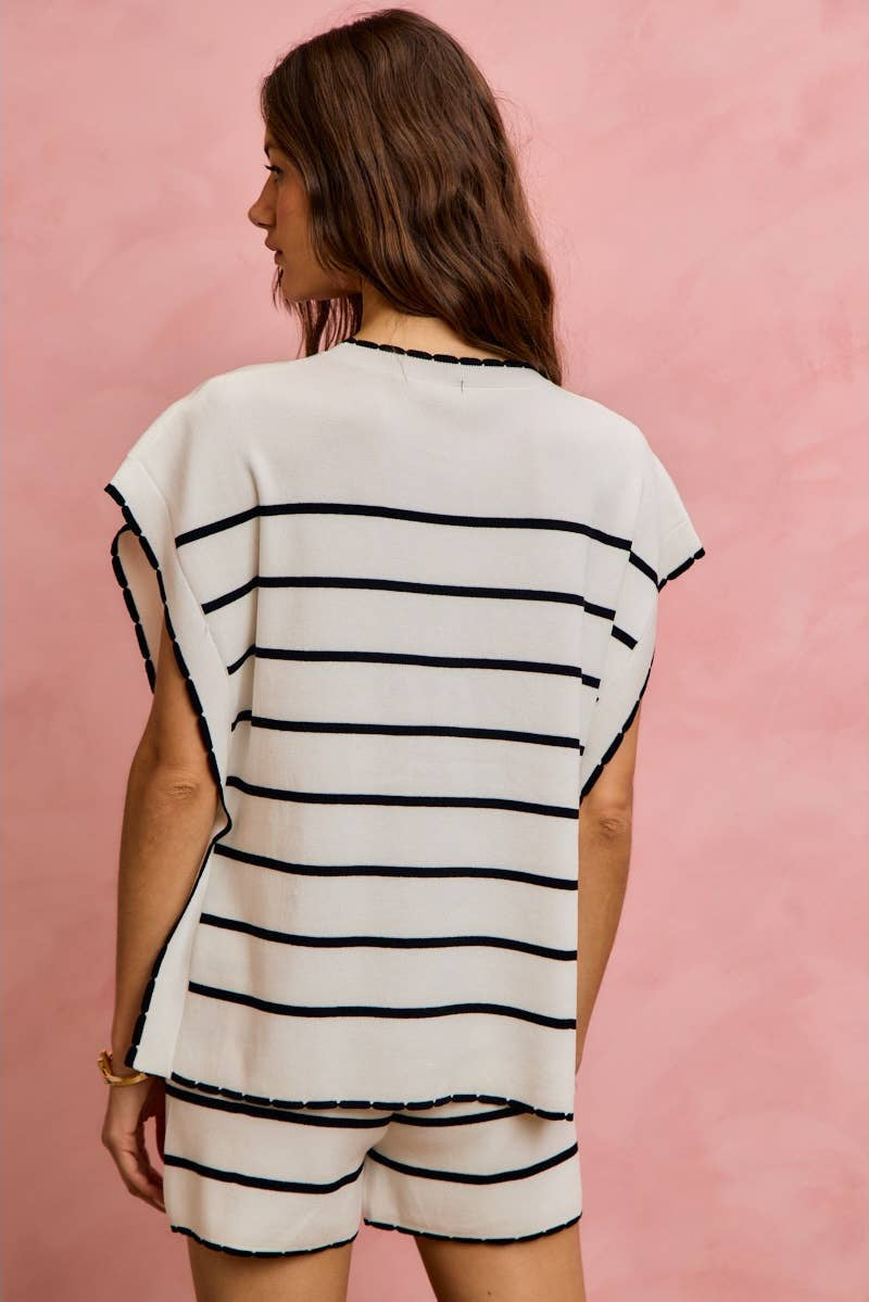 Woman wearing a black and white striped outfit against a pink background