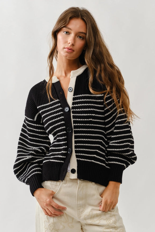 Woman wearing a black and white striped cardigan on a plain background