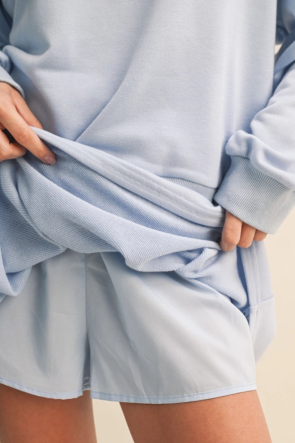 Person wearing a light blue outfit with shorts and a sweatshirt.