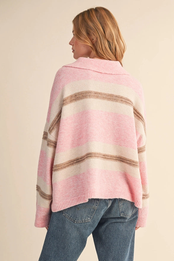 Person wearing a pink and brown striped sweater with a beige background