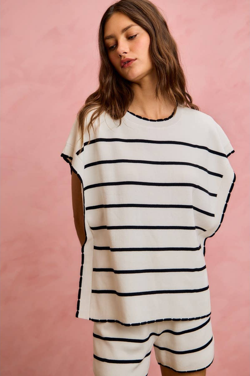 Woman wearing a black and white striped outfit against a pink background