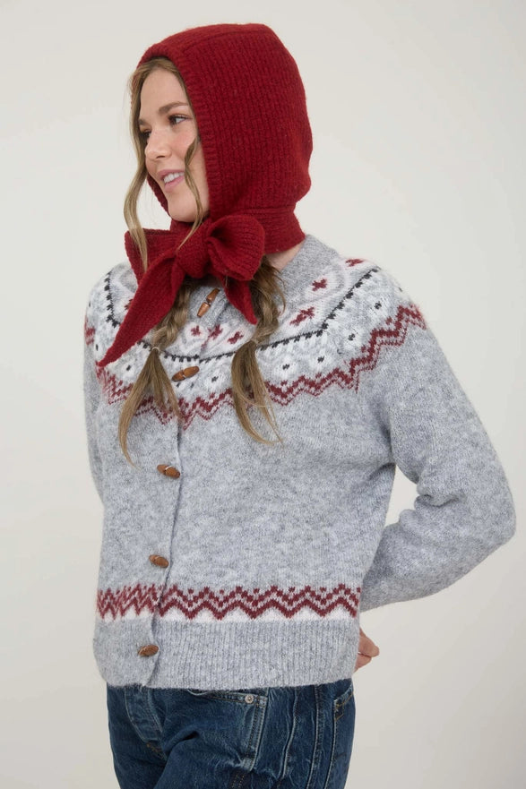 Person wearing a gray sweater with red patterns and a matching red bonnet on a white background