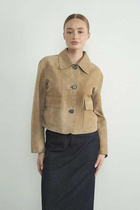 Woman wearing a beige suede jacket against a plain background