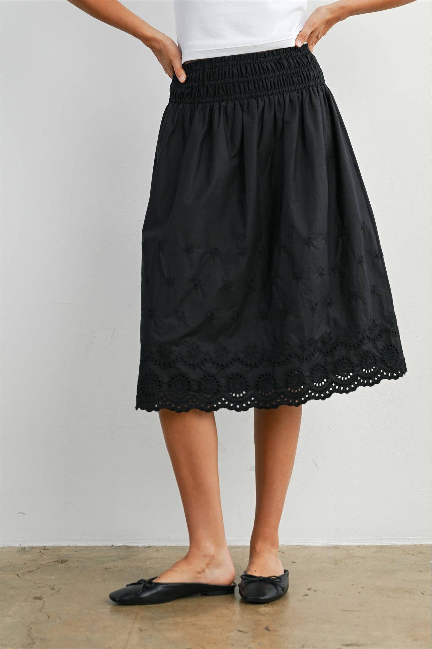 Black lace skirt worn by a person on a plain background