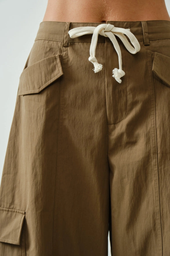 Brown cargo pants with a white drawstring on a light gray background