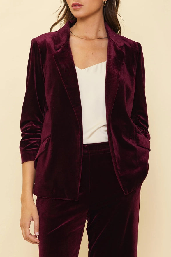 Burgundy velvet suit with a white top on a beige background