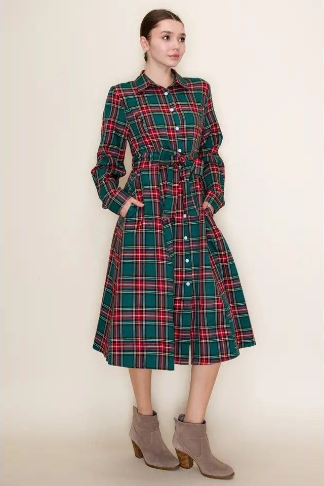 Woman wearing a green plaid dress with a belt on a beige background