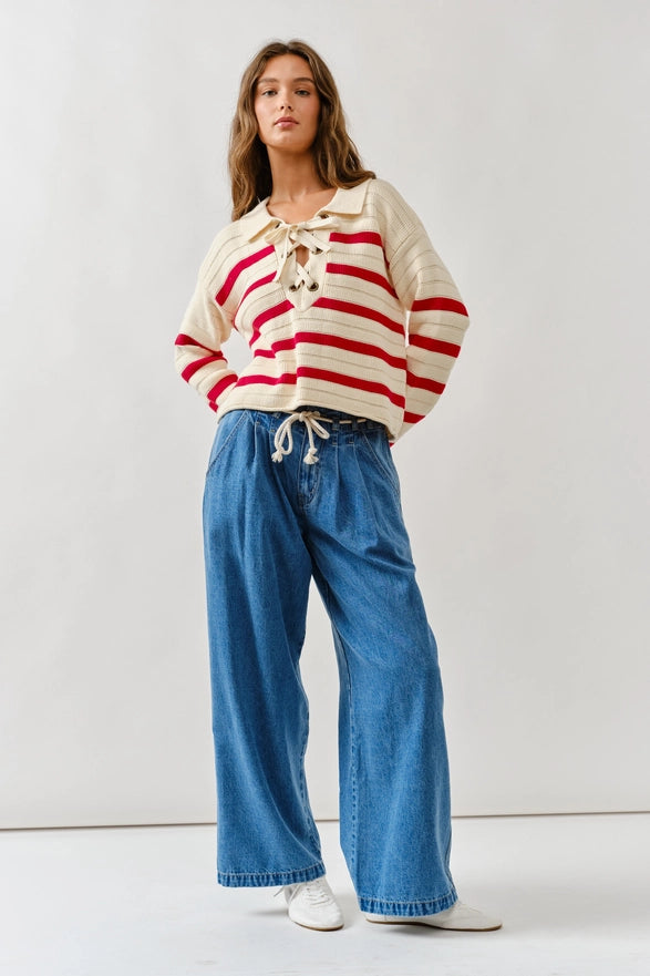 Woman wearing a red and white striped shirt with a beige collar and blue jeans on a white background