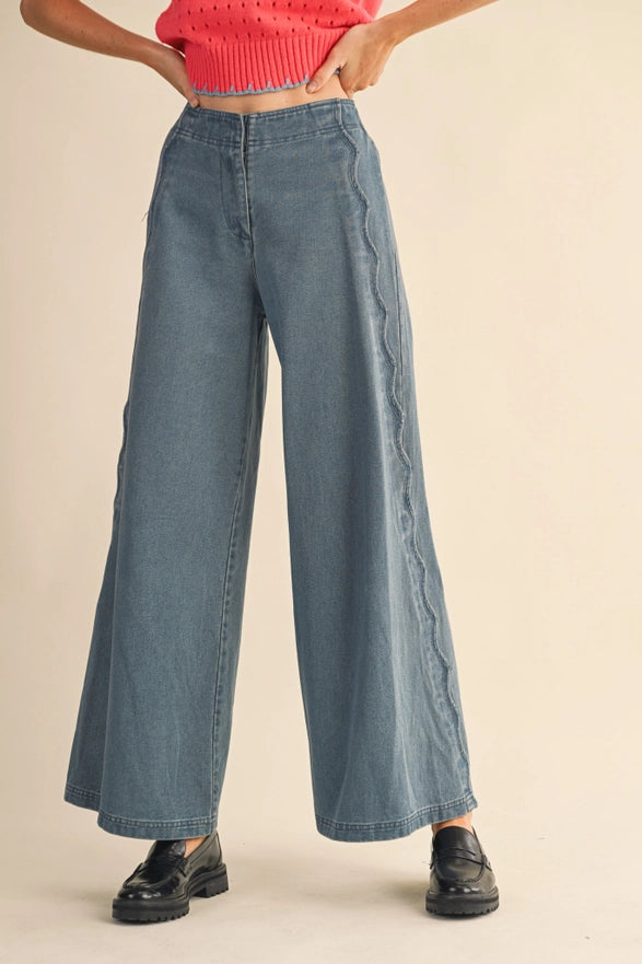 Person wearing blue wide-leg jeans and a red top on a beige background