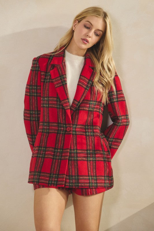 Woman wearing a red plaid blazer and shorts against a beige background