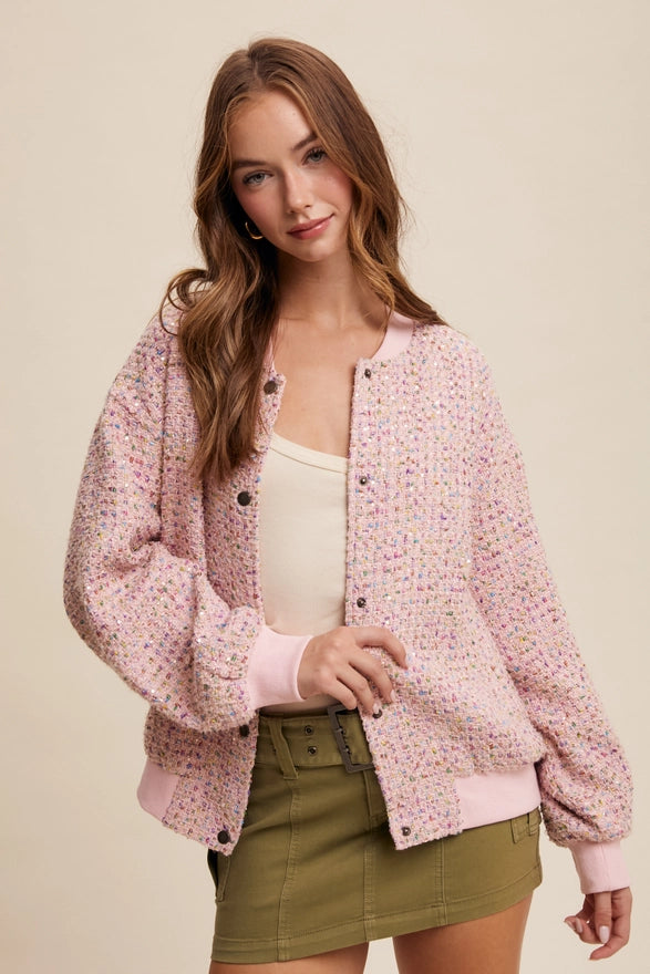 Woman wearing a pink floral jacket over a beige top and green shorts on a beige background