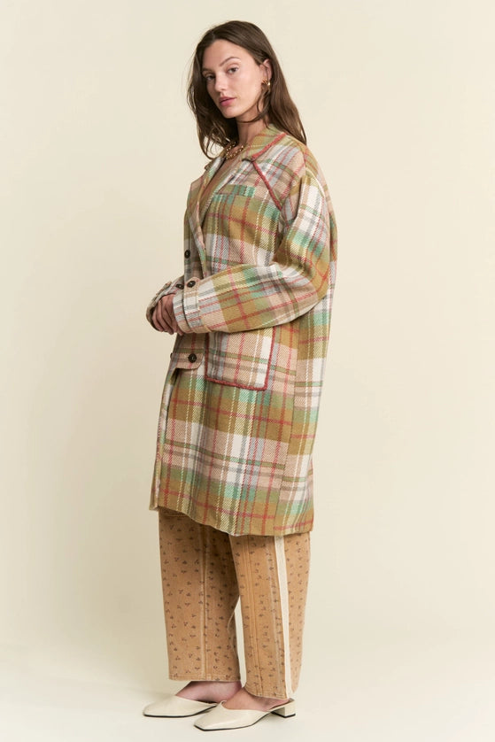 Woman wearing a plaid coat and pants against a plain background